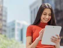 Young smiling businesswoman holding digital tablet, check email, working online on the street