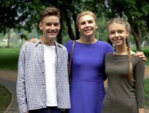 Mother posing in front of a camera with her two kids, smiling