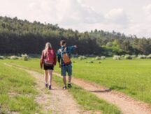 Two young adults, male and female, with backpacks, enjoying time together during a hike on a beautiful sunny spring day.