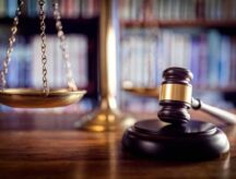 A picture of a gavel and scales, in a court room.