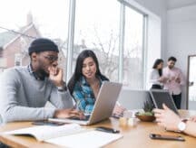 Students stare at a laptop on a table in front of them