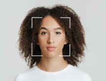 Picture of a woman in the viewfinder of a camera, with a scanner projected onto her face.