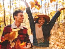 A man and a woman surrounded by fall foliage