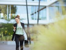 A woman in a suit smiles while checking her phone